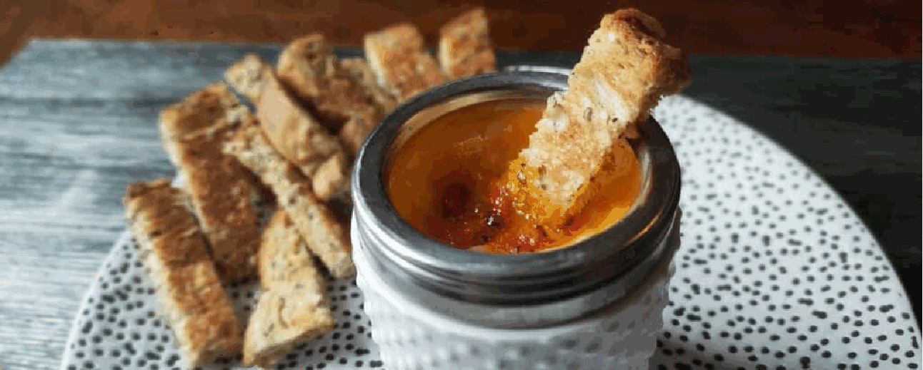 Coddled egg served in a porcelain egg coddler with toast soldiers